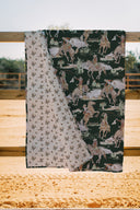 quilt blanket on a wooden surface, one with floral pattern and the other with horse and rider design.