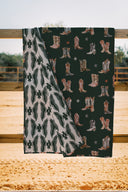 blanket with cowboy boot pattern on a wooden surface